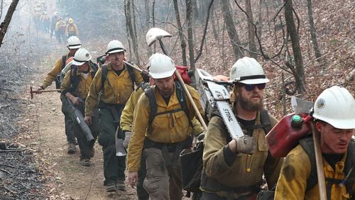 An incoming California fire crew (right) walks in after working over night on the northern head of the Rock Mountain Fire along the Appalachian Trail at Deep Gap while a outgoing Oregon fire crew (far left) bumps them heading out for their long shift. The area is deep in the Natahala National Forest. Curtis Compton/ccompton@ajc.com