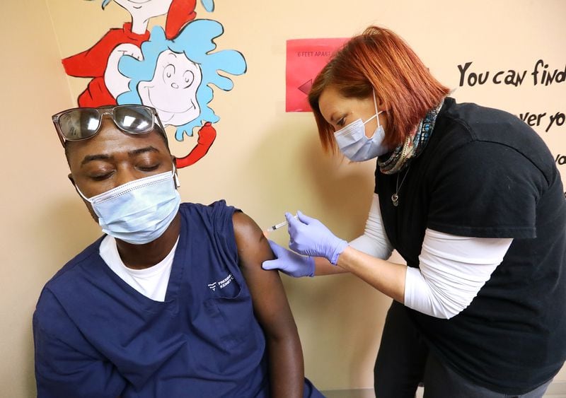 Dialysis technician Mohammed Olugbeja closes his eyes while paramedic Traci Turner administers his Moderna COVID-19 vaccination at the Paulding County Health Department in Dallas, Ga. on Tuesday.   (PHOTO by Curtis Compton / Curtis.Compton@ajc.com)