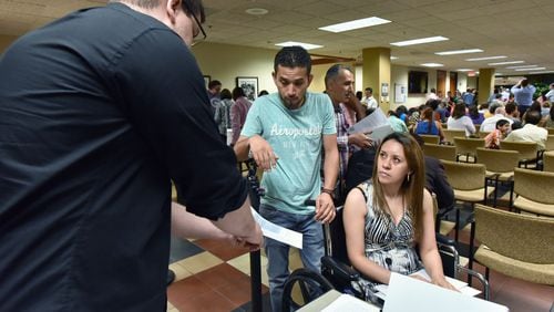 Nick Marshall (left), with ProGeorgia, helps newly naturalized citizens Sergio Almanza and his wife Maria Tapia, both originally from Mexico, with their voting registrations after their naturalization ceremony at the USCIS Atlanta Field Office in 2016. HYOSUB SHIN / HSHIN@AJC.COM  AJC File Photo