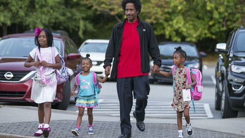 William White IV walks his daughters Allison White (from left), Amber White (second from left) and Ashley White (right) to M. Agnes Jones Elementary School on Friday during the national Million Fathers March Day in Atlanta’s Ashview Heights neighborhood. Fathers Incorporated, a local nonprofit, helped with welcoming the students and dads to the school. ALYSSA POINTER / ALYSSA.POINTER@AJC.COM