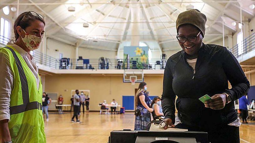 Cobb County Poll Clerk Andrea Keener (left) assists Smyrna resident Qris Dorvil as she places her ballot in the electronic ballot machine at the Smyrna Community Center.