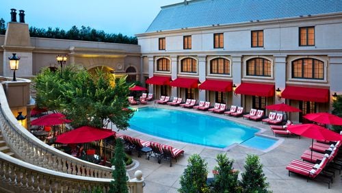 The St. Regis Atlanta Pool Piazza features red-and-white lounge chairs and a dramatic cascading waterfall.
