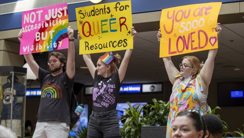 Seth Lee, Bo Bowman and Gracie Lee hold up signs during a protest LGBTQ students at Georgia Southern University held Monday. The peaceful protest was in response to moves the university's leadership recently made involving health care and inclusion on the campus in Statesboro. (AJC Photo/Katelyn Myrick)