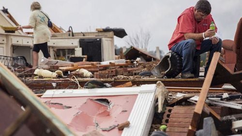 Jeff Bullard sits in what used to be the foyer of his home as his daughter, Jenny Bullard, looks through debris at their home that was damaged by a tornado Sunday in Adel. Gov. Nathan Deal declared a state of emergency in 16 counties. (Credit: Branden Camp / Associated Press)