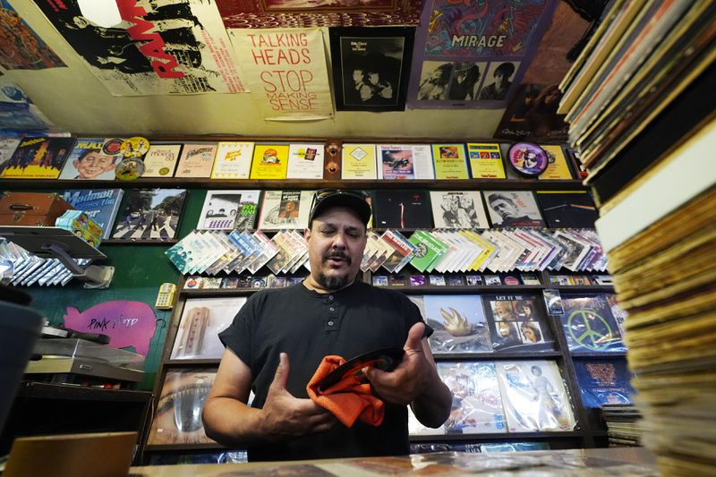Tim Stamper, owner at Tracks In Wax record shop, cleans off some vinyl 45s at his shop, Thursday, April 18, 2024, in Phoenix. Special LP releases, live performances and at least one giant block party are scheduled around the U.S. Saturday as hundreds of shops celebrate Record Store Day amid a surge of interest in vinyl and the day after the release of Taylor Swift's latest album. (AP Photo/Ross D. Franklin)