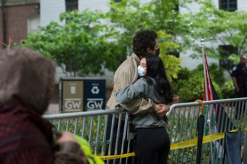 George Washington University students, who declined to provide their names, hug during a protest of the Israel-Hamas war at George Washington University in Washington, Saturday, April 27, 2024. The student at left is inside the fence of the school's University Yard, unable to leave because he would not be allowed back in. (AP Photo/Cliff Owen)