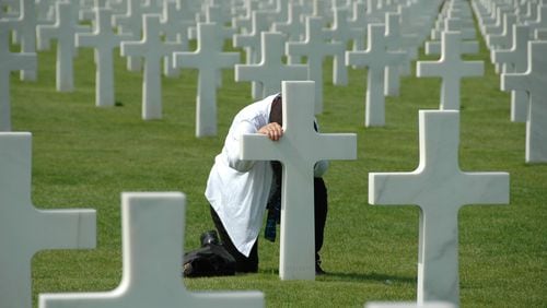 Dimitri Dodys took this picture during a visit to Normandy France in August 2017. The unidentified man was kneeling in prayer at this grave site. The Normandy American Cemetery and Memorial in France is located in Colleville-sur-Mer, on the site of the temporary American St. Laurent Cemetery, established by the U.S. First Army on June 8, 1944 as the first American cemetery on European soil in World War II. The cemetery site, at the north end of its half mile access road, covers 172.5 acres and contains the graves of 9,385 of American military dead, most of whom lost their lives in the D-Day landings and ensuing operations. On the Walls of the Missing, in a semicircular garden on the east side of the memorial, are inscribed 1,557 names. Rosettes mark the names of those since recovered and identified.