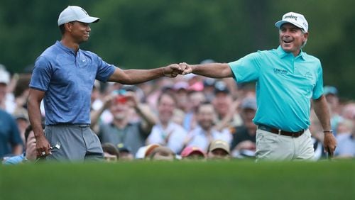 Tiger Woods and Fred Couples exchange a fist bump after they both hit their tee shots close to the cup on the par-3 no. 12 hole at Amen Corner while playing a practice round for the Masters at Augusta National Golf Club on Monday, April 8, 2019, in Augusta.    Curtis Compton/ccompton@ajc.com