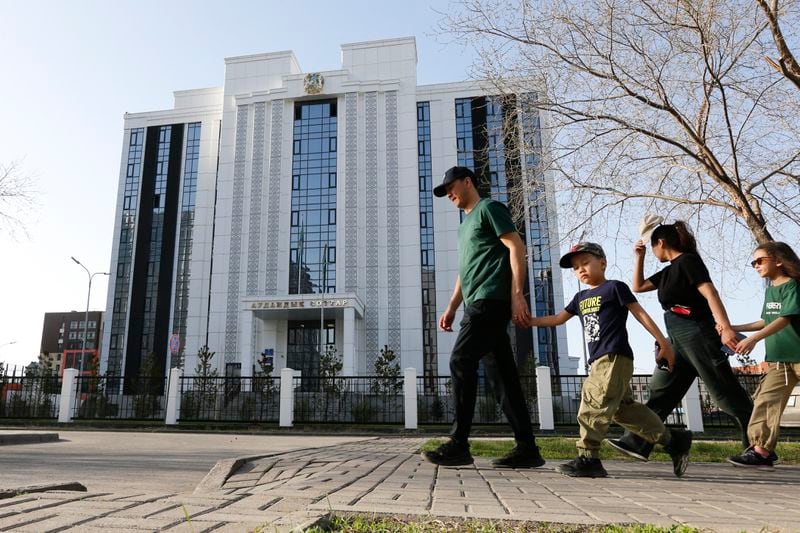 A family walks past the courthouse where the trial of former Economics Minister Kuandyk Bishimbayev is taking place in Astana, Kazakhstan, on Sunday, April 21, 2024. Bishimbayev, charged with killing his wife, Saltanat Nukenova, has touched a nerve in the Central Asian country. Tens of thousands of people have signed petitions calling for harsher penalties for domestic violence, and on April 11, senators approved a bill toughening penalties for spousal abuse, and President Kassym-Jomart Tokayev signed the measure into law four days later. (AP Photo/Stanislav Filippov)