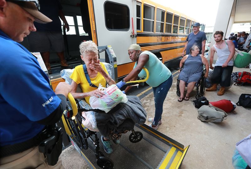  Glynn County school resource officer Mark Hooper (left) and school support staff member Sheree Armstrong (right) help an emotional Elizabeth Scales board a special needs school bus in Brunswick at Lanier Plaza as hundreds of local residents evacuate the area ahead of Hurricane Dorian.   Curtis Compton/ccompton@ajc.com