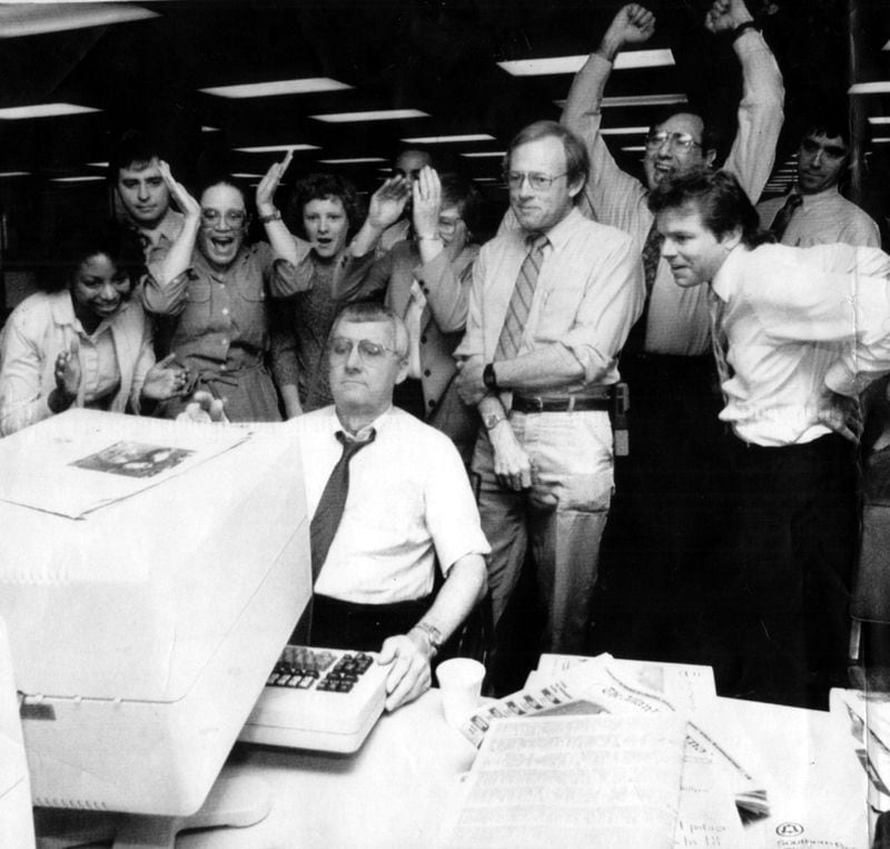 Atlanta, Ga.: March 30, 1989 - Herb Steely, seated at computer, and other staffers read the announcement of the Pulitzer Prize for investigative reporting to the Atlanta Journal Constitution in their Atlanta newsroom. The winning series of stories about alleged 'redlining' of minority neighborhoods by Atlanta banks was written by Bill Dedman. (Neil Brake/AP) 1989