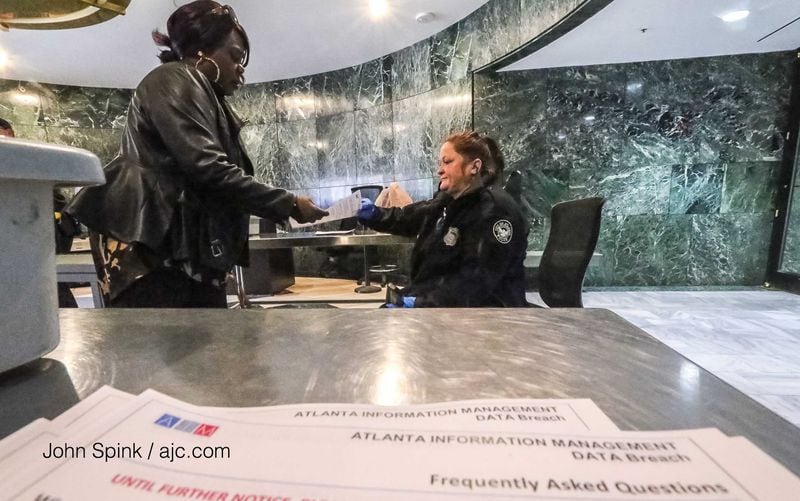 Kim Nelson (left) with the city of Atlanta AIM (IT dept) (left) receives a flyer instructing employees not to turn on computer or logon from Atlanta police officer K. Wilkins (right) at the front doors of Atlanta City Hall.