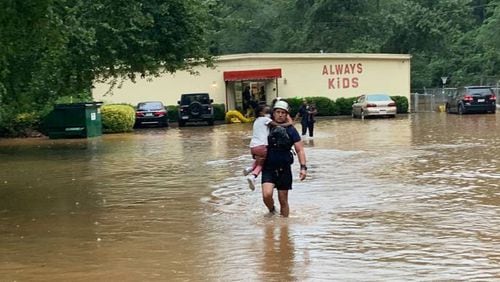 A firefighter removes a child from an Austell day care after heavy rain flooded the parking lot.