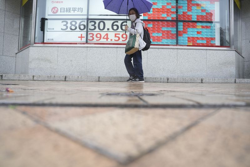 A person walks in the rain near an electronic stock board showing Japan's Nikkei 225 index at a securities firm Tuesday, May 7, 2024, in Tokyo. (AP Photo/Eugene Hoshiko)