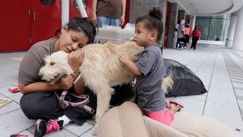 Tiffany Duron and her daughter Emma Sledge, 3, hug their dog Daisy on Aug. 30, 2017, outside the George R. Brown Convention Center where they took shelter after Hurricane Harvey flooded their home in Houston.