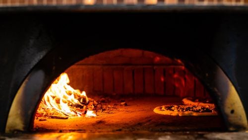 Pizzas bake in one of the wood-fired pizza ovens at Ammazza. CONTRIBUTED BY HENRI HOLLIS