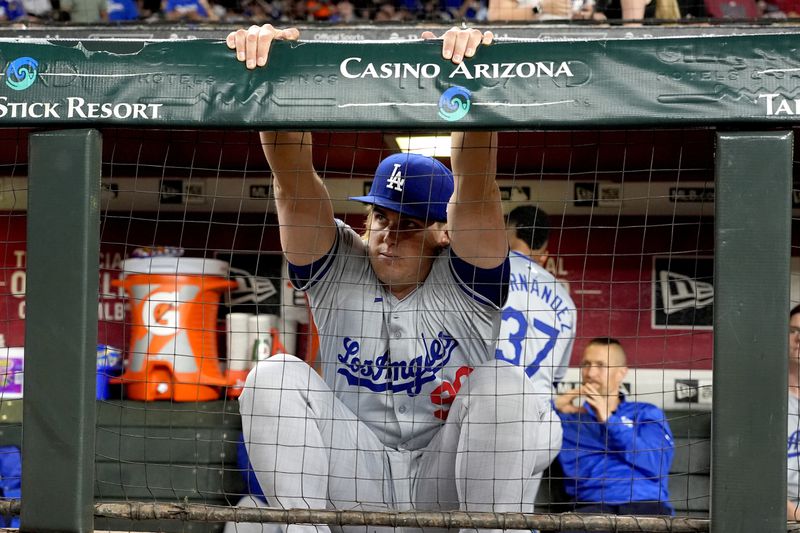Los Angeles Dodgers starting pitcher Landon Knack stretches while a swarm of bees gathered on the net behind home plate are removed delaying the start of a baseball game between the Los Angeles Dodgers and the Arizona Diamondbacks, Tuesday, April 30, 2024, in Phoenix. (AP Photo/Matt York)