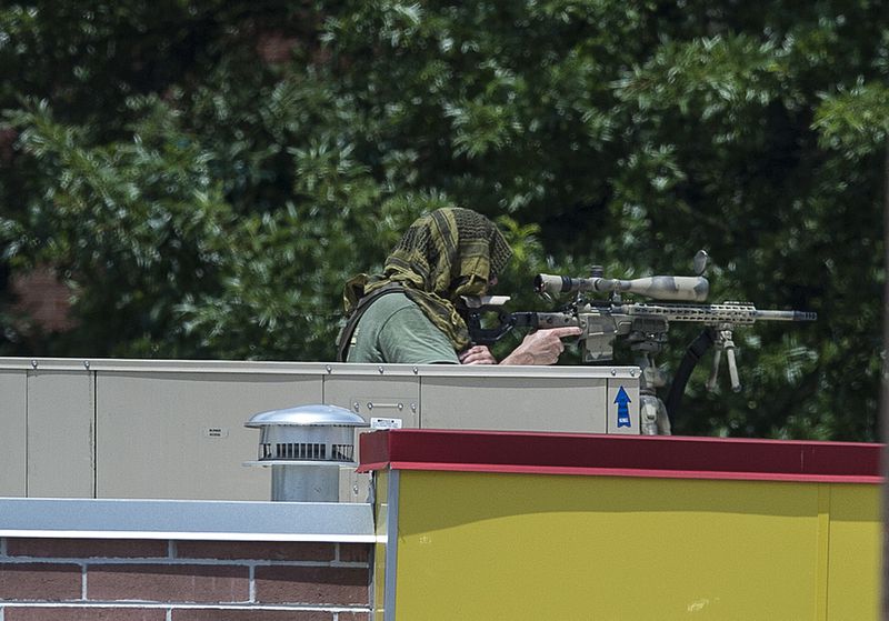 A police sniper sits atop a restaurant near a Wells Fargo Bank, Friday, July 7, 2017 in Marietta, Ga. A man who claimed to have a bomb that could "take out the room" barricaded himself inside a suburban Atlanta bank Friday, sparking an hours-long standoff that forced police to bust through a brick wall of the building and later ended with the suspect's death.(AP Photo/Mike Stewart)(AP Photo/Mike Stewart)