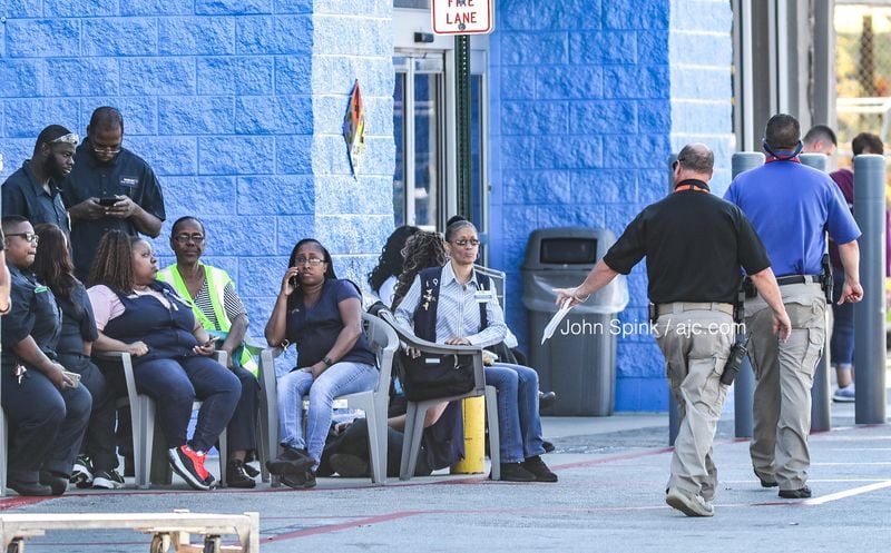 Walmart employees sit outside the store Wednesday morning as investigators work to determine what led to the stabbing.