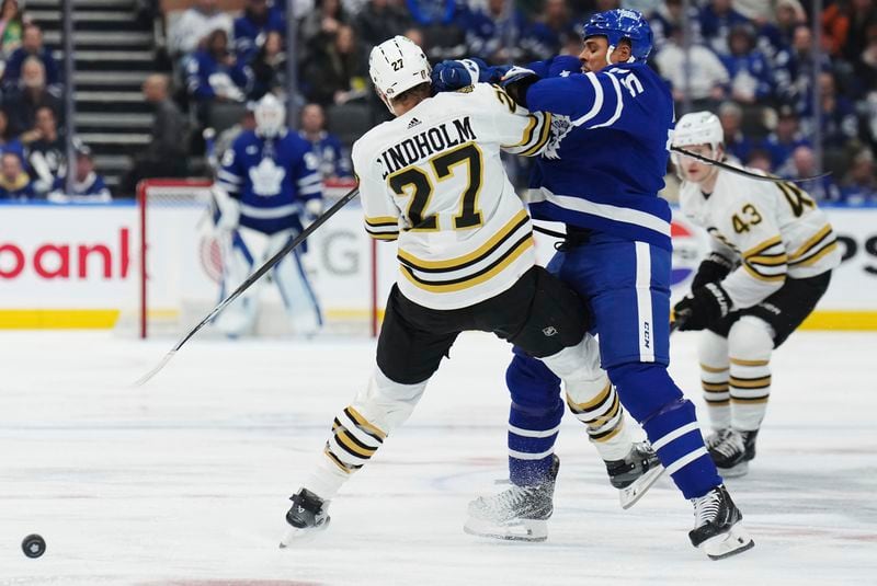 Toronto Maple Leafs' Ryan Reaves (front right) hits Boston Bruins' Hampus Lindholm (27) during the second period of action in Game 3 of an NHL hockey Stanley Cup first-round playoff series in Toronto on Wednesday, April 24, 2024. (Nathan Denette/The Canadian Press via AP)