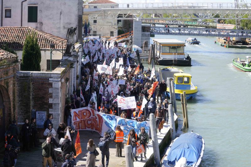 Citizens and activists stage a protest against Venice Tax Fee in Venice, Italy, Thursday, April 25, 2024. The fragile lagoon city of Venice begins a pilot program Thursday to charge daytrippers a 5 euro entry fee that authorities hope will discourage tourists from arriving on peak days. The daytripper tax is being tested on 29 days through July, mostly weekends and holidays starting with Italy's Liberation Day holiday Thursday. Officials expect some 10,000 people will pay the fee to access the city on the first day, downloading a QR code to prove their payment, while another 70,000 will receive exceptions, for example, because they work in Venice or live in the Veneto region. (AP Photo/Luca Bruno)
