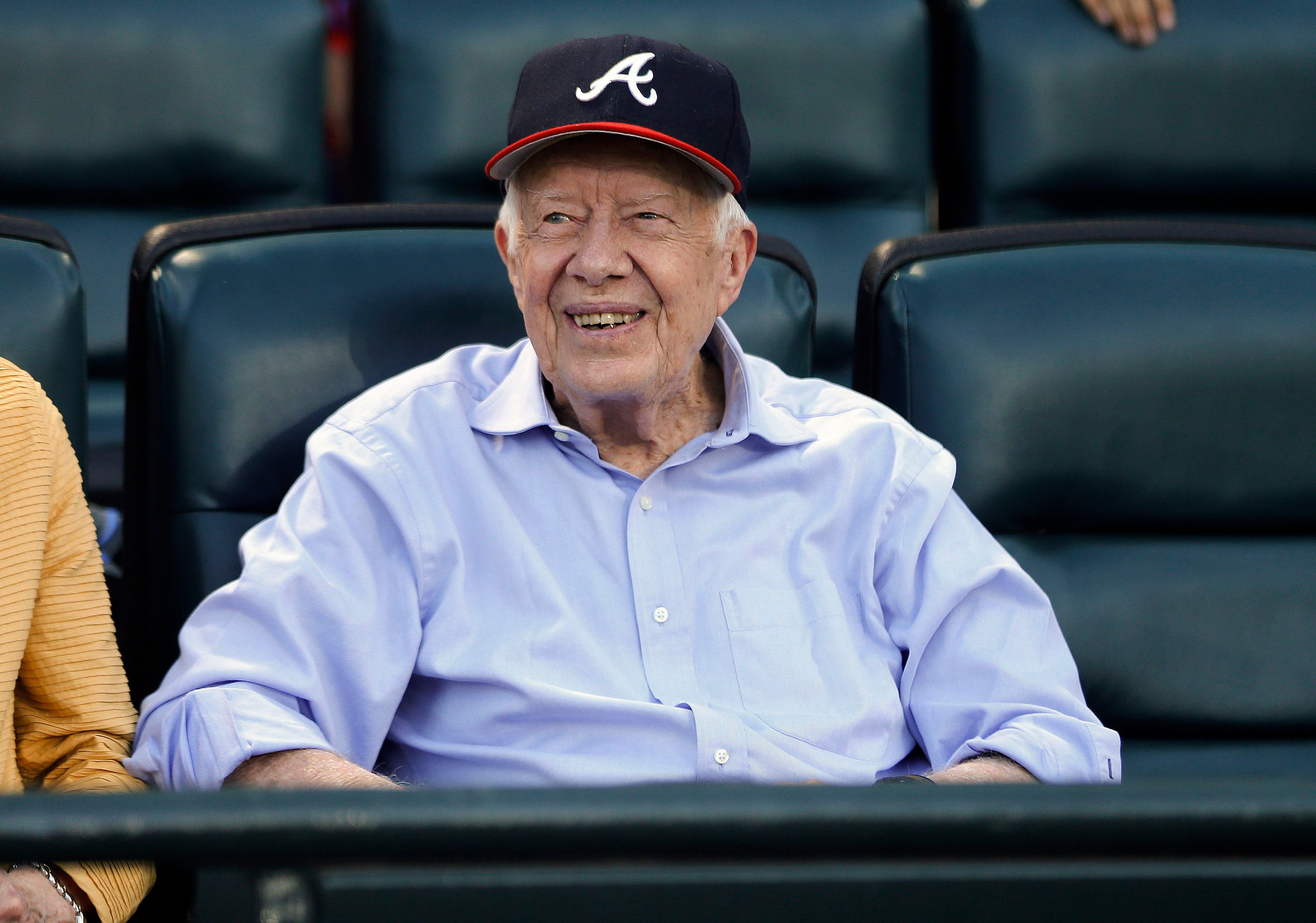 Atlanta Braves fan former President Jimmy Carter cheers during the seventh  inning stretch as a group sings God Bless America during Game 3 of the  National League Championship Series at Turner Field