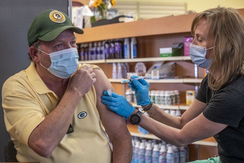 In this file photo, Dunwoody resident Randy Krafft, 64, left, receives his second Moderna COVID-19 vaccination from pharmacist Leslie Juhn at Concord Carlton's Pharmacy in Dunwoody. Emory University is participating in a COVID-19 vaccine booster study. (Alyssa Pointer / Alyssa.Pointer@ajc.com)