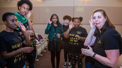 Cecilia Forbes (right) leads the DeKalb Early College Academy Sign Language Club members in practice before they perform Christmas carols while signing during the schools holiday show in Stone Mountain. (Photo by Phil Skinner)
