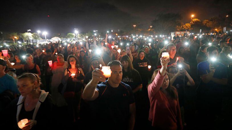 People participate in a candlelight vigil in memory of the 17 students and faculty who were killed in the Wednesday mass shooting at Marjory Stoneman Douglas High School in Parkland, Fla., Monday, Feb. 19, 2018. Nikolas Cruz, a former student, was charged with 17 counts of premeditated murder on Thursday. (AP Photo/Gerald Herbert)