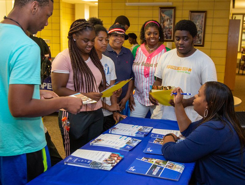 Georgia State University’s DiAna Kelley (seated) talks to a group of students during a college and career expo hosted at Fredrick Douglass High School, in Atlanta, on Wednesday, July 24, 2019, as part of a program offering summertime support to recent Atlanta high school graduates. (Photo by Phil Skinner)