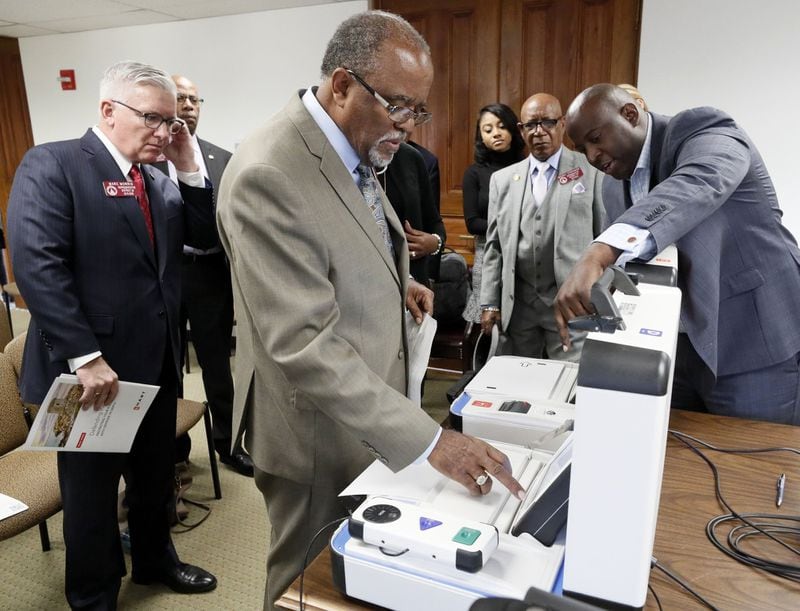 Dwayne Broxton, right, the regional sales director for Hart InterCivic, walks state Rep. Al Williams, D-Midway, through the process of voting, during a demonstration in January of his company’s voting machines to lawmakers. Bob Andres / bandres@ajc.com