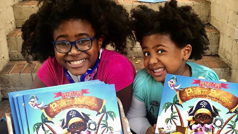 Selah Thompson, founder of The Empowered Readers Literacy Project with her little sister, Syrai, shown with the first book of Selah's "Penelope the Pirate Princess" series.