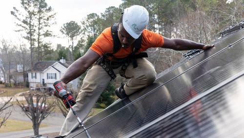 Mike Harris, an installer for Creative Solar USA, installs solar panels on a home in Ball Ground, Ga., on December 17, 2021.