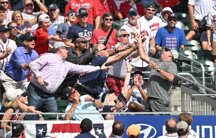 Braves fans grab a foul ball during the fourth inning of game one of the baseball playoff series between the Braves and the Phillies at Truist Park in Atlanta on Tuesday, October 11, 2022. (Hyosub Shin / Hyosub.Shin@ajc.com)