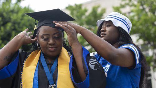 Latonya Young’s friend Essence Johnson helps her with her cap and gown at Georgia State University’s student center in downtown Atlanta, Georgia, on April 29, 2021. Young, a 44-year-old mother of three, will finally graduate from Georgia State University after numerous breaks in her education journey due to hardships. (Rebecca Wright for The Atlanta Journal-Constitution)