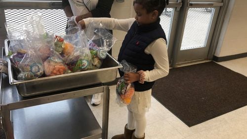 Lily Lambert, 7, picks up food distributed Monday at North Clayton Middle School.