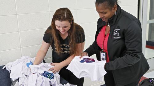 Nikki Rajahn shows North Fayette Elementary School Principal Lisa Moore some of the T-shirt designs from a schoolwide competition encouraging students to submit anti-bullying designs and uplifting slogans. For the first day of school, her son Blake, a subject of bullying, wore a personalized T-shirt that said “I Will Be Your Friend” to reach out to others who might need a friend. BOB ANDRES / ROBERT.ANDRES@AJC.COM