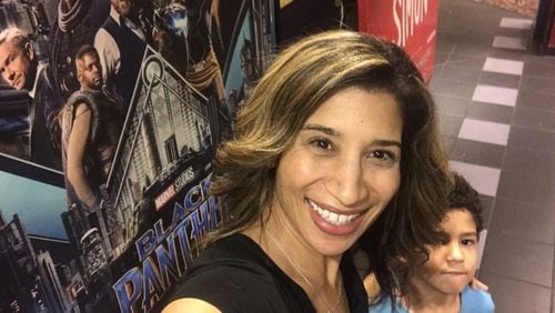 Debra Shigley, founder of Colour, an in-home beauty salon, takes a selfie with her son in front of a “Black Panther” movie poster. Shigley, 38, said the natural hairstyles in the blockbuster are reason enough to celebrate. CONTRIBUTED