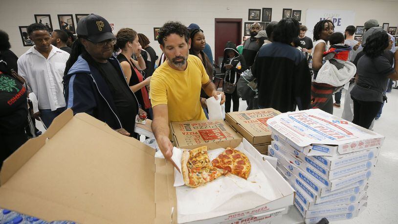 Angel Poventud, who voted early, volunteers his time to hand out pizza and snacks to people waiting in line. The wait time to vote at the Pittman Park precinct in Atlanta was reported to be three hours. Pizza and snacks were donated for the people waiting in line. BOB ANDRES / BANDRES@AJC.COM