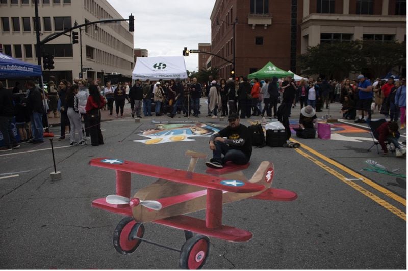 Hector Diaz poses on his completed artwork at this year’s Chalktoberfest. He created an airplane for guests to “fly” on. (Photo Courtesy of Jen Curtis/Fresh Take Georgia)