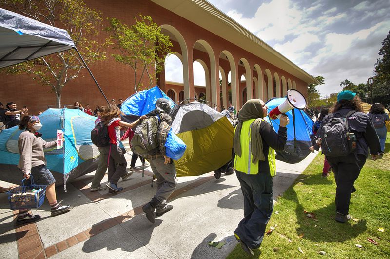 University of Southern California protesters carry a tents around Alumni Park on the University of Southern California to keep security from removing them during a pro-Palestinians occupation on Wednesday, April 24, 2024 in Los Angeles. (AP Photo/Richard Vogel)
