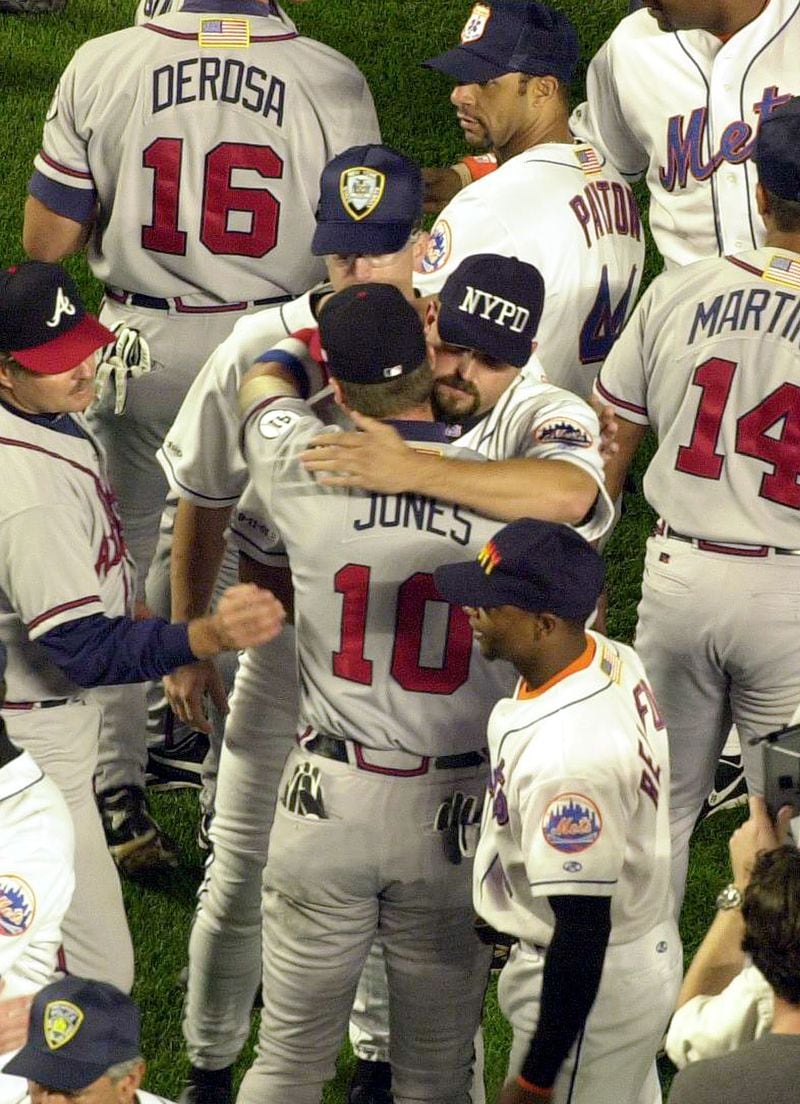 The Mets' Rick White, wearing an NYPD cap, embraces the Braves'  Chipper Jones before the start of the Sept. 21, 2001, game at Shea Stadium, the first MLB game in New York after the World Trade Center attack of Sept. 11. The Mets wore caps honoring the police and fire departments for the game. (Mark Lennihan/AP)