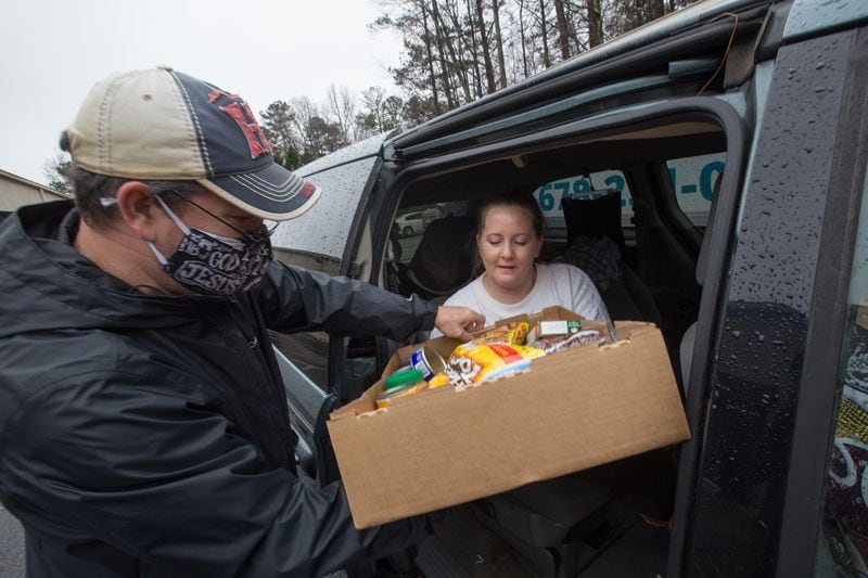 Volunteering at the food bank, Mark Jeffreys, left, distributes dry goods, fresh vegetables and frozen meats to Jenny Allison, right, at New City Church in Peachtree City. (Jenni Girtman for The Atlanta Journal-Constitution)