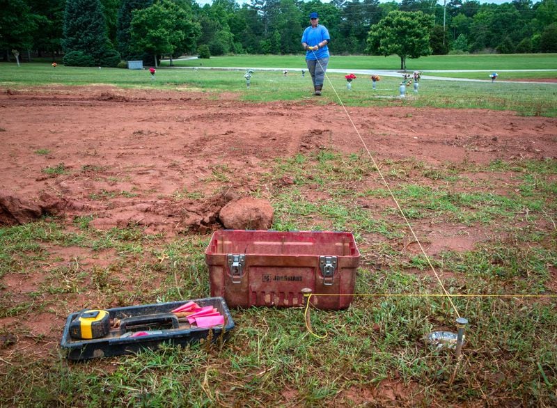 Sher Lemons measures out the dimensions for new pauper burial sites at Lakeside Memorial Gardens. (Steve Schaefer for The Atlanta Journal-Constitution)