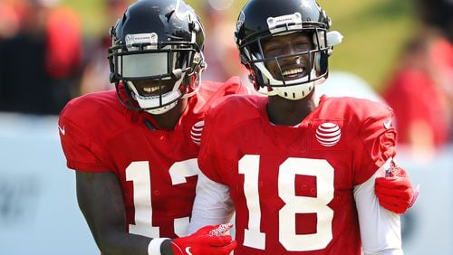 Falcons wide receiver Calvin Ridley (right) gets some encouragement from wide receiver Christain Blake after catching a pass while getting in some light work during team practice Monday, July 29, 2019, in Flowery Branch.