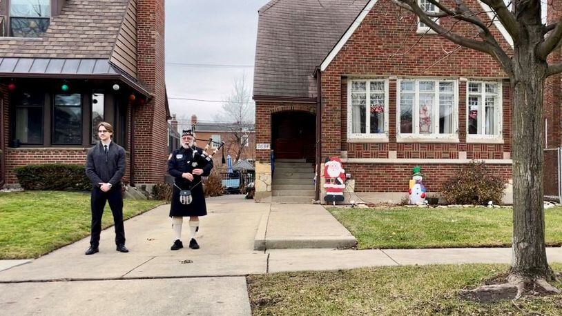 Chicago Police Department bagpiper Don McGrath bids farewell to Helen Gilligan Torpy outside her home as the funeral procession passes.