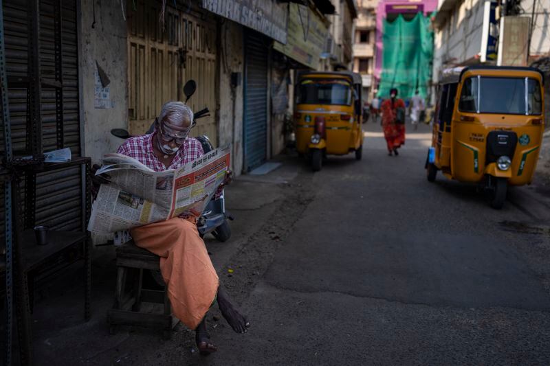 An elderly man reads a newspaper in an alleyway in the southern Indian city of Chennai, April 16, 2024. (AP Photo/Altaf Qadri)