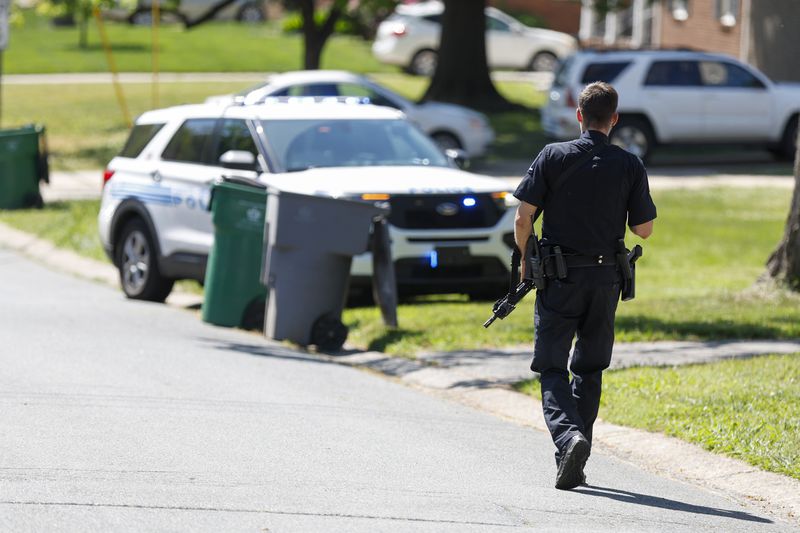 A Charlotte Mecklenburg police officer walks carrying a gun in the neighborhood where an officer-involved shooting took place in Charlotte, N.C., Monday, April 29, 2024. The Charlotte-Mecklenburg Police Department says officers from the U.S. Marshals Task Force were carrying out an investigation Monday afternoon in a suburban neighborhood when they came under gunfire. (AP Photo/Nell Redmond)