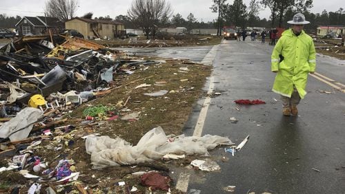 ADDS DATE - A Georgia state trooper walks past a mobile home destroyed by severe weather in Adel, Ga., Monday, Jan. 23, 2017. Gov. Nathan Deal declared a state of emergency in several counties, including Cook, that have suffered deaths, injuries and severe damage from weekend storms and expanded it Monday to include additional counties in southern Georgia. (AP Photo/Brendan Farrington)