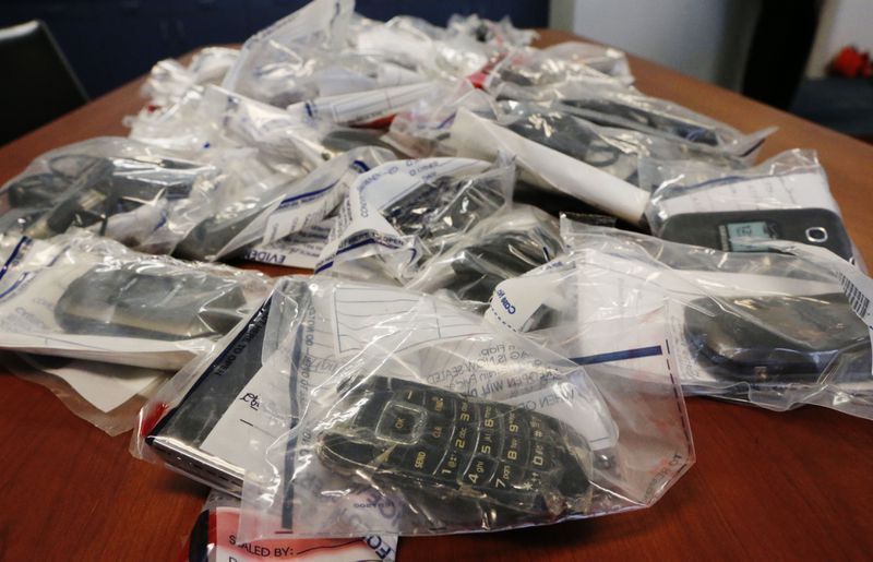 Confiscated cell phones were on display at a 2015 press conference. Federal authorities had obtained indictments that allege two groups of inmates used cell phones inside state prisons to run a drug ring across the metro area and perpetrate fraud schemes against individuals outside the prison walls. BOB ANDRES / BANDRES@AJC.COM